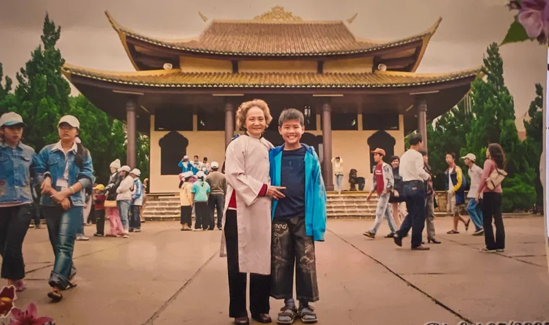 Huan as a young boy standing with his grandmother in front of a temple